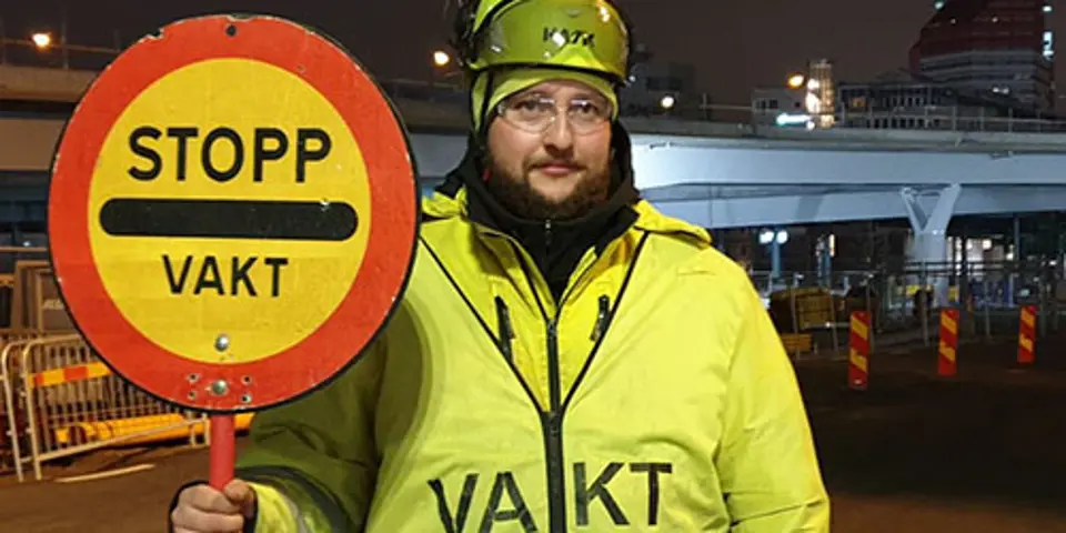 Vägvakten Denny håller stoppsignal längs en väg